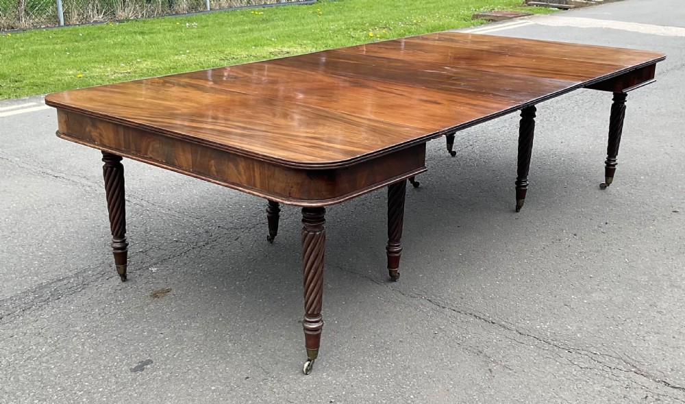 A large Regency mahogany extending dining table featuring spiral-turned legs fitted with brass castors. View V