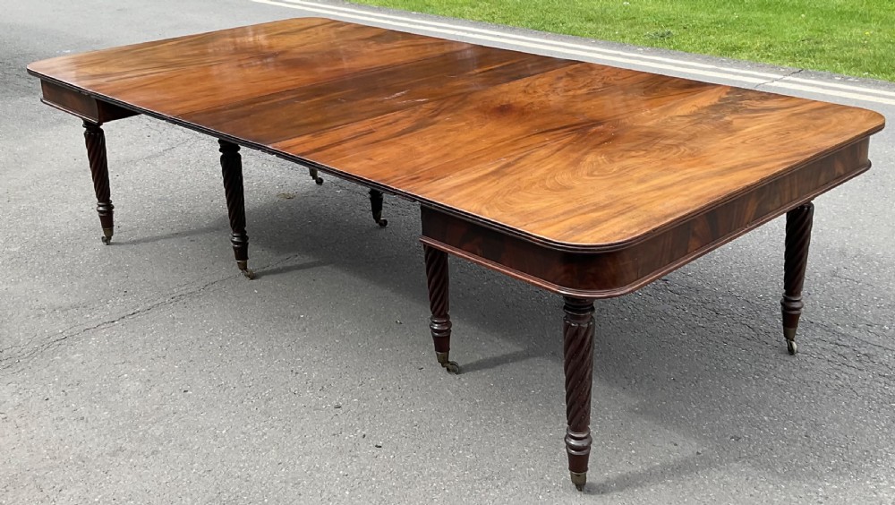 A large Regency mahogany extending dining table featuring spiral-turned legs fitted with brass castors. View VIII