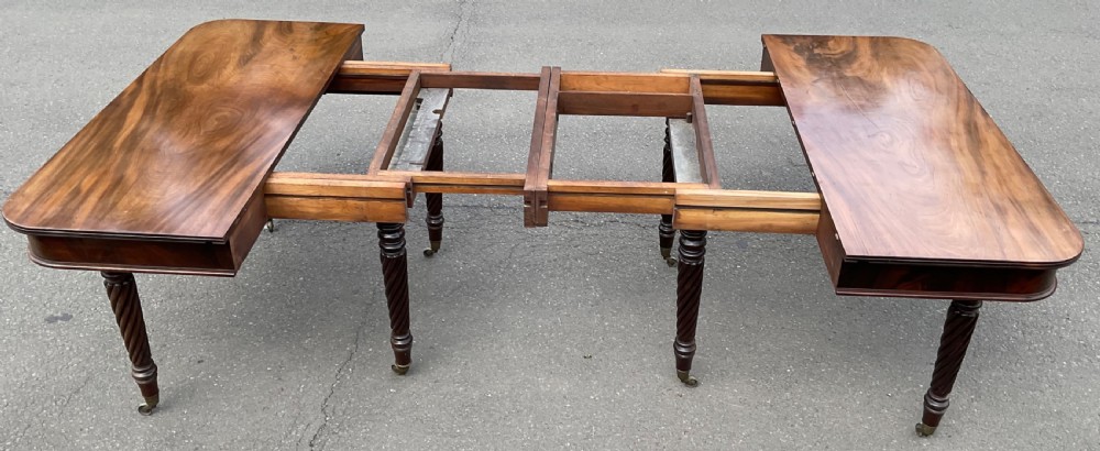 A large Regency mahogany extending dining table featuring spiral-turned legs fitted with brass castors. View X
