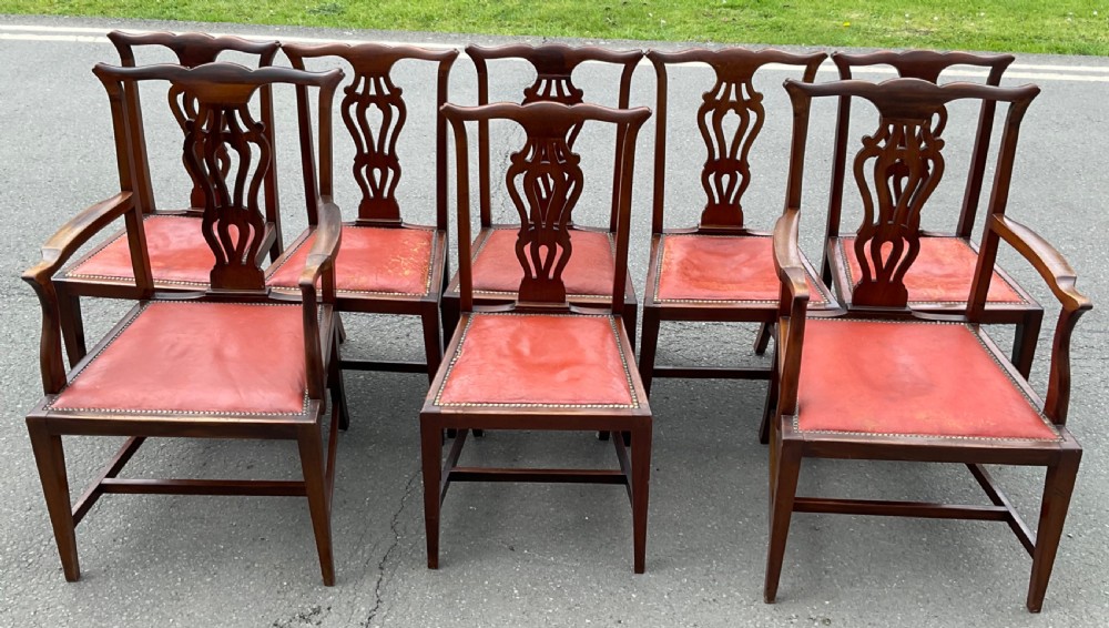A set of eight Edwardian mahogany dining chairs featuring pierced back splats, square legs with stretchers, and red leather seats detailed with brass studding. View II