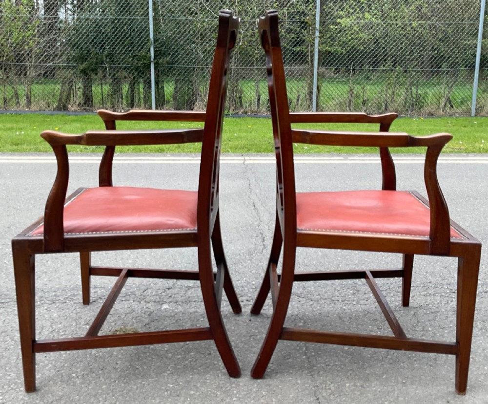 A set of eight Edwardian mahogany dining chairs featuring pierced back splats, square legs with stretchers, and red leather seats detailed with brass studding. View VI