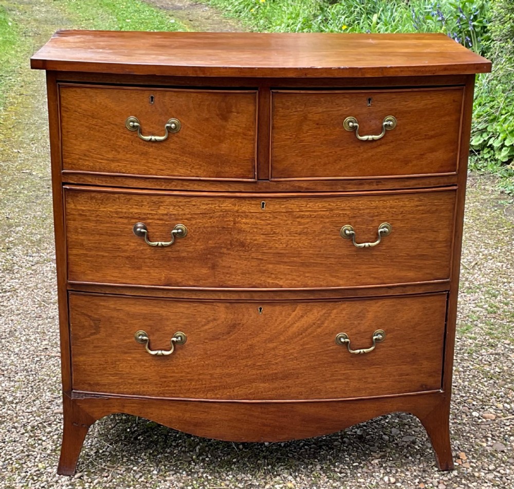 A Georgian mahogany chest of drawers featuring a curved bowfront facade, brass swan-neck handles, keyholes, and splayed bracket feet.