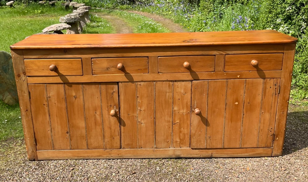 A long Victorian pine sideboard featuring four upper drawers above plank-fronted cupboard doors with turned wooden knobs. View II