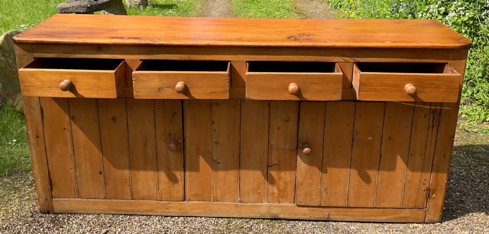 A long Victorian pine sideboard featuring four upper drawers above plank-fronted cupboard doors with turned wooden knobs. View VII