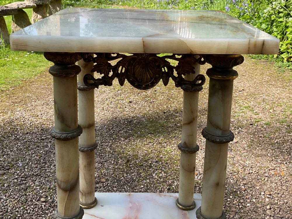 A two-tier square plant stand constructed from cream veined onyx with four cylindrical onyx columns and ornate cast brass feet and mounts. View VIII
