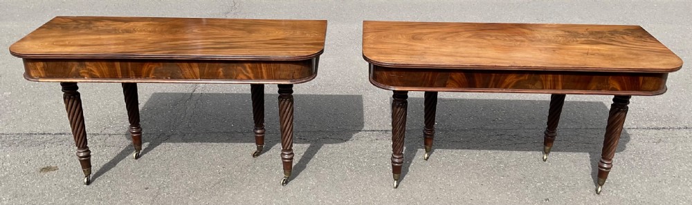 A matching pair of early nineteenth-century Regency mahogany console tables featuring spiral-carved legs on brass castors and rounded corners.