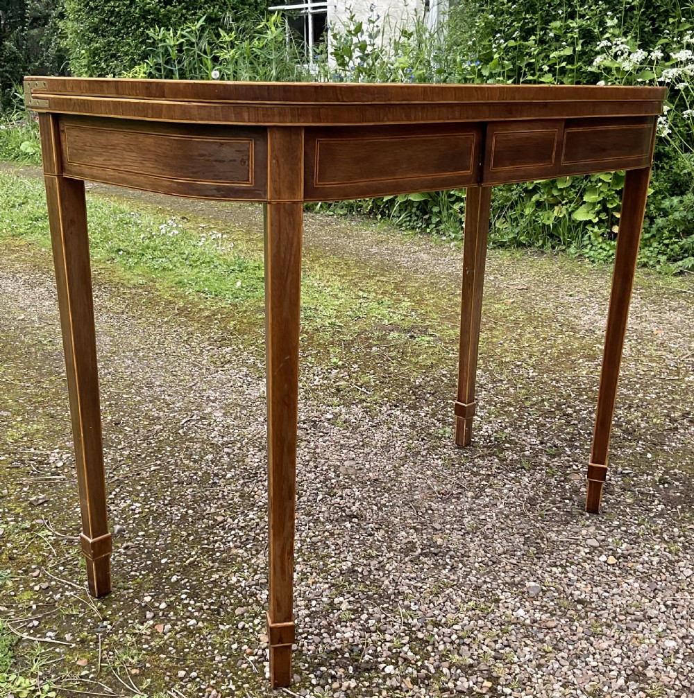 A Georgian inlaid mahogany foldover tea table featuring a rounded rectangular top, linear boxwood stringing, and square tapered legs. View II