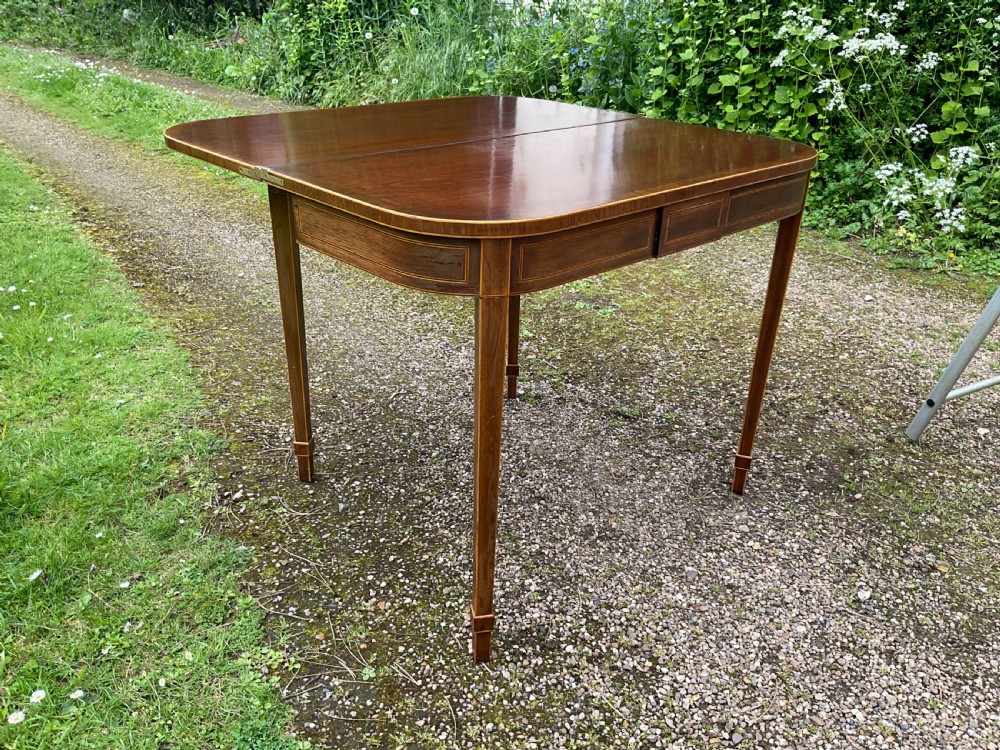 A Georgian inlaid mahogany foldover tea table featuring a rounded rectangular top, linear boxwood stringing, and square tapered legs. View IV