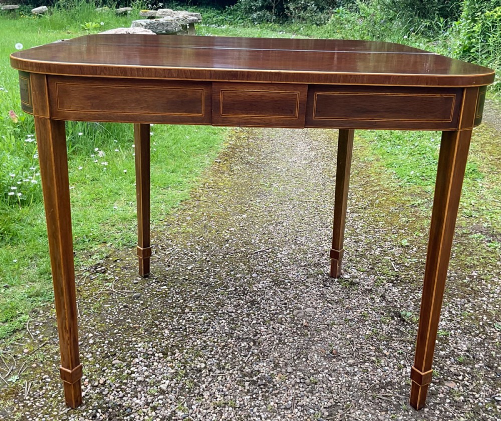 A Georgian inlaid mahogany foldover tea table featuring a rounded rectangular top, linear boxwood stringing, and square tapered legs. View V