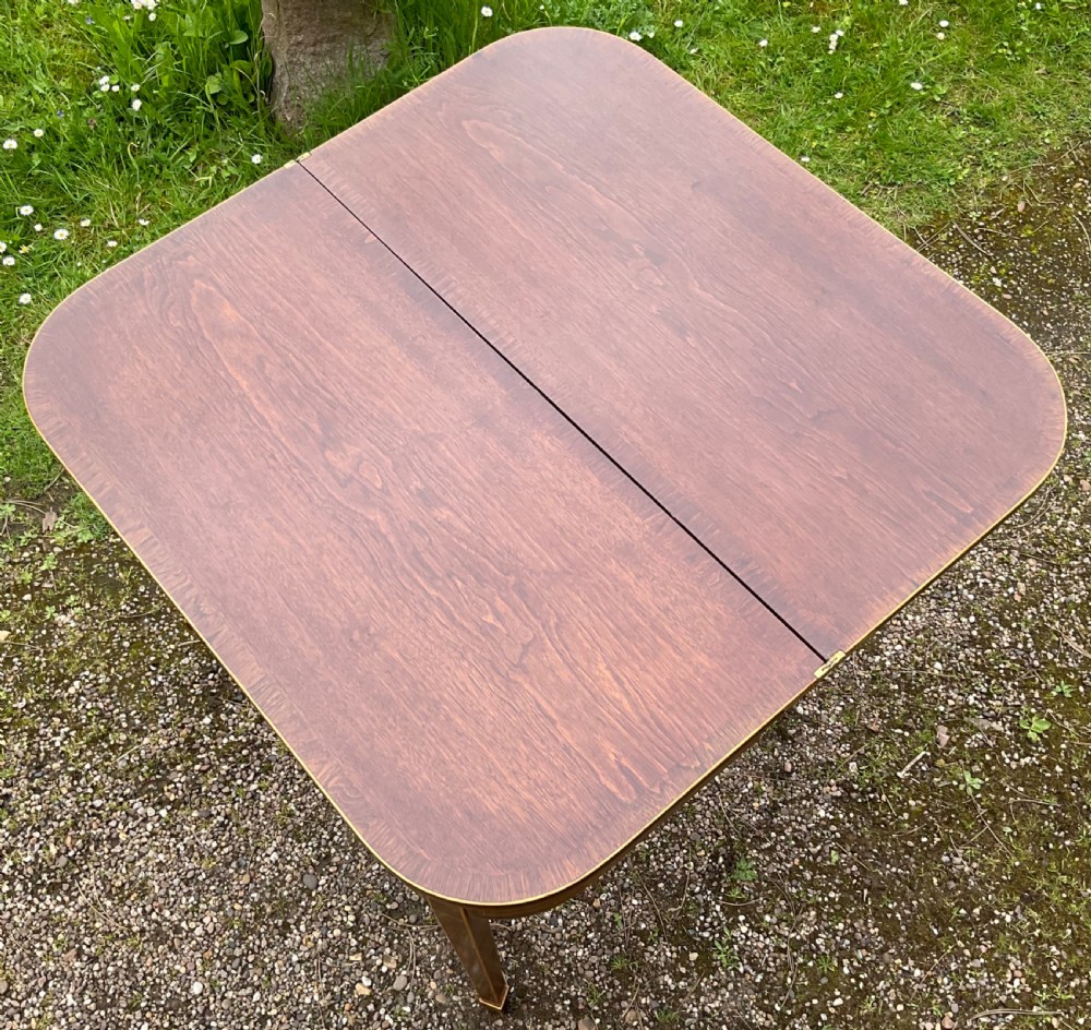 A Georgian inlaid mahogany foldover tea table featuring a rounded rectangular top, linear boxwood stringing, and square tapered legs. View VI