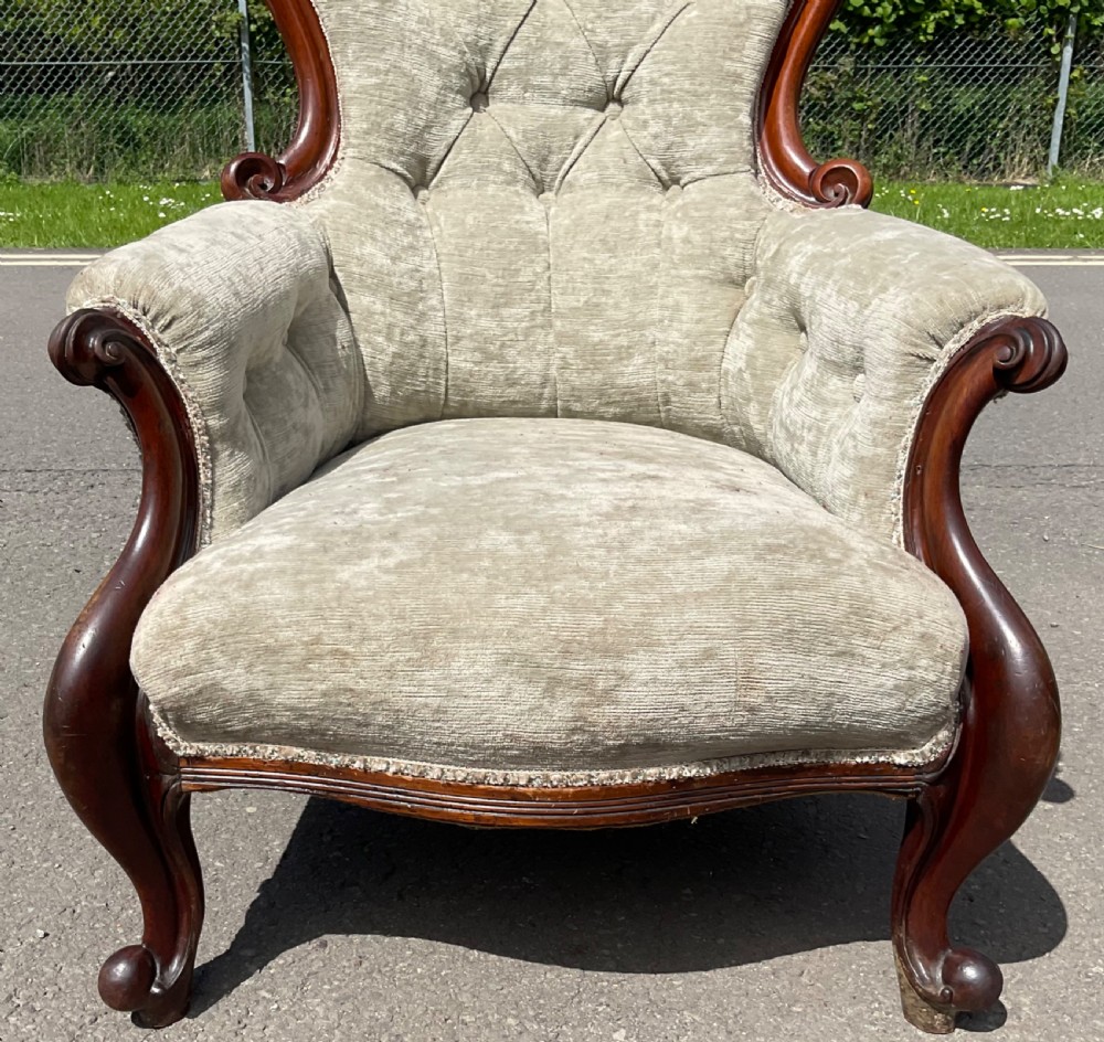 A Victorian mahogany armchair featuring a button-tufted light beige velvet spoon backrest, padded armrests with scroll accents, and carved cabriole legs. View V