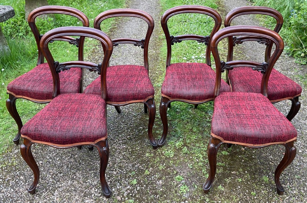 Set of six Victorian rosewood balloon back dining chairs featuring carved mid-rails, cabriole front legs, and red textured upholstered seats. View II