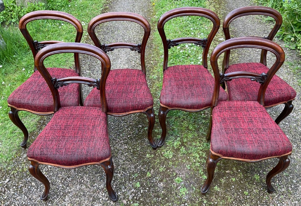 Set of six Victorian rosewood balloon back dining chairs featuring carved mid-rails, cabriole front legs, and red textured upholstered seats. View IV