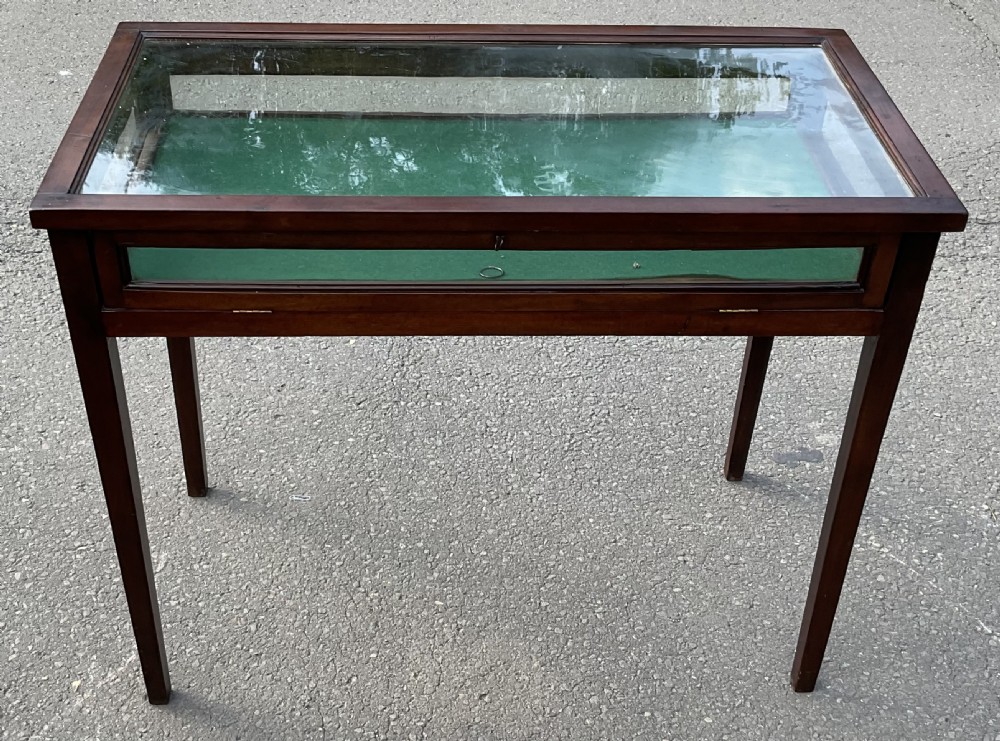 An Edwardian mahogany display table featuring a rectangular glass top, glazed sides, a green baize interior base, and slender square tapered legs. View II