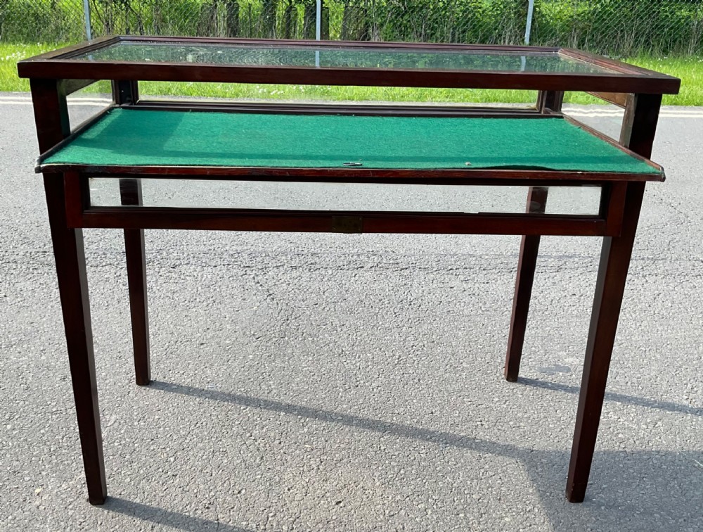 An Edwardian mahogany display table featuring a rectangular glass top, glazed sides, a green baize interior base, and slender square tapered legs. View V