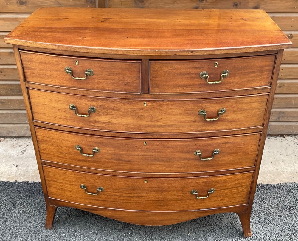 A Georgian mahogany bowfront chest featuring two short drawers over three long drawers with brass drop handles and splayed bracket feet. View II