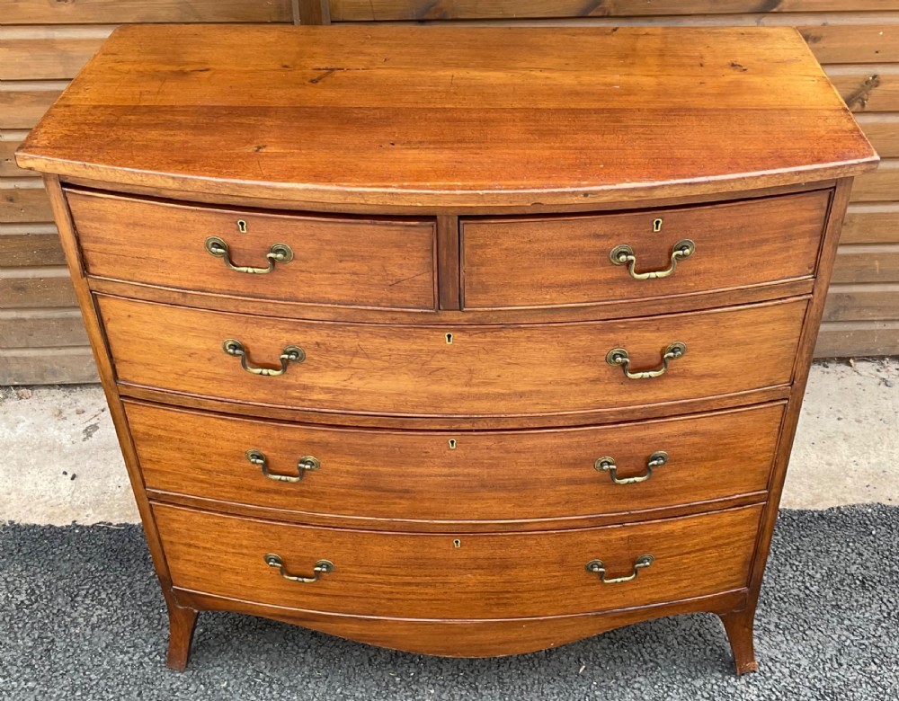 A Georgian mahogany bowfront chest featuring two short drawers over three long drawers with brass drop handles and splayed bracket feet. View IV