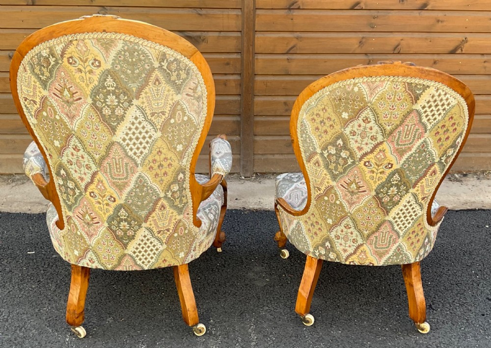 A pair of Victorian carved walnut salon chairs featuring deep buttoned patterned upholstery, spoon backs, scroll arms, and cabriole legs on castors. View VIII