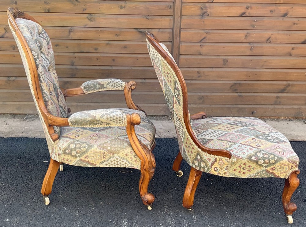 A pair of Victorian carved walnut salon chairs featuring deep buttoned patterned upholstery, spoon backs, scroll arms, and cabriole legs on castors. View IX
