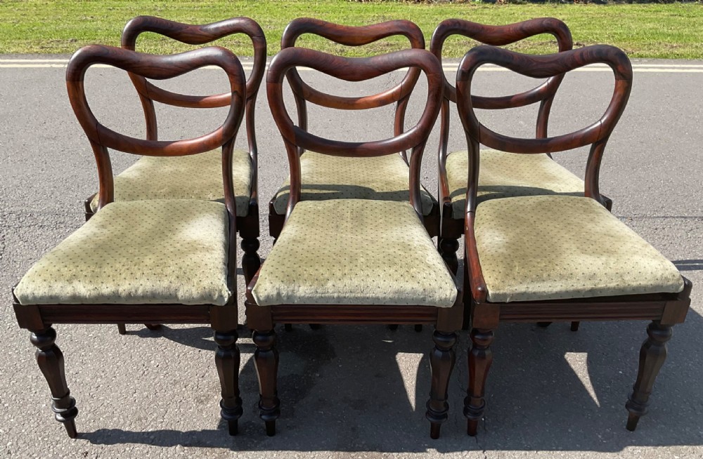 A set of six Victorian rosewood balloon back dining chairs with green velvet upholstered seats and turned front legs.