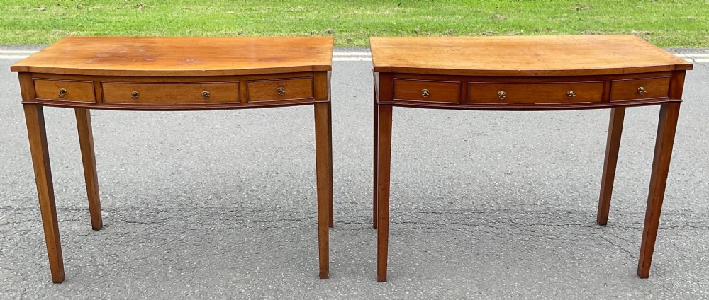 A pair of Georgian-style mahogany side tables featuring gentle bowfronts, drawer fronts with brass ring handles, and square tapered legs. View II