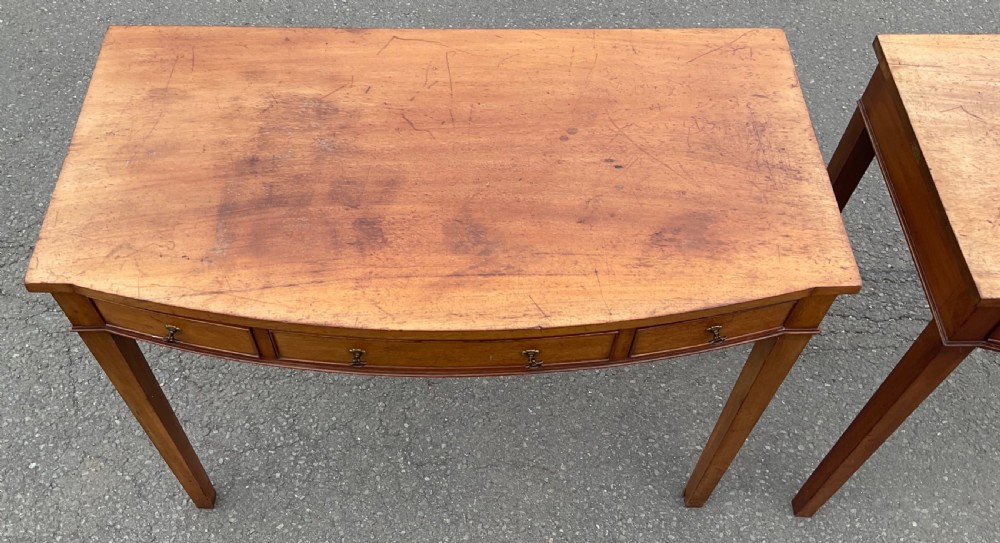 A pair of Georgian-style mahogany side tables featuring gentle bowfronts, drawer fronts with brass ring handles, and square tapered legs. View IX