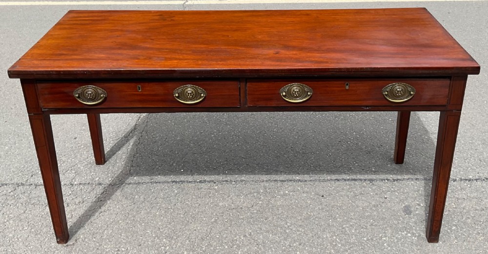 A rectangular Georgian mahogany serving table featuring two frieze drawers with oval brass handles, raised on four tapered square legs.