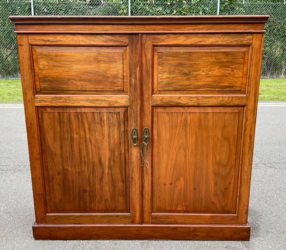 A nineteenth-century Victorian mahogany bedroom cupboard featuring two doors with flame wood panels, brass handles, and a solid plinth base.