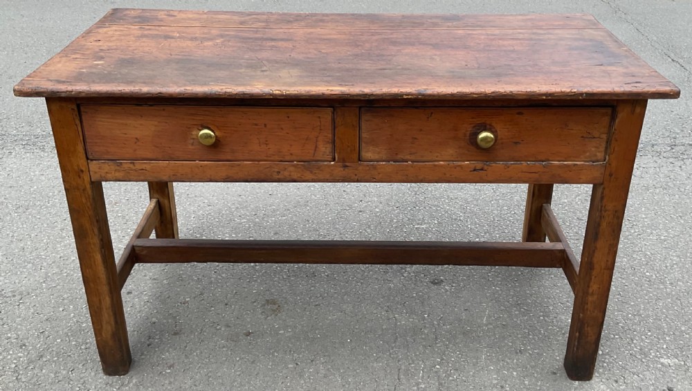 A nineteenth-century Victorian pine kitchen table featuring two front drawers with metal knobs, square legs, and a central stretcher rail.
