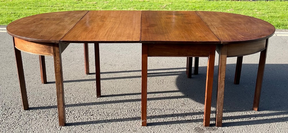 A large Georgian extending mahogany dining table featuring D-end sections, central extension leaves, and straight square legs.