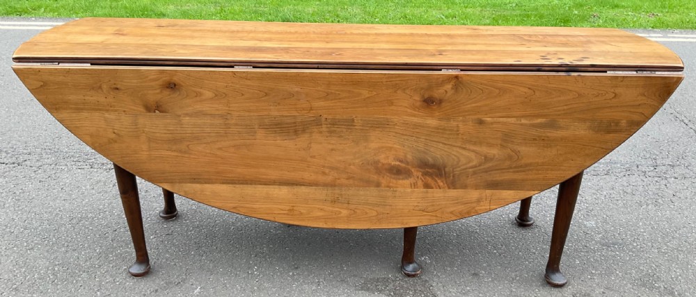 A large Georgian mahogany drop-leaf dining table featuring hinged side flaps and turned legs terminating in pad feet.