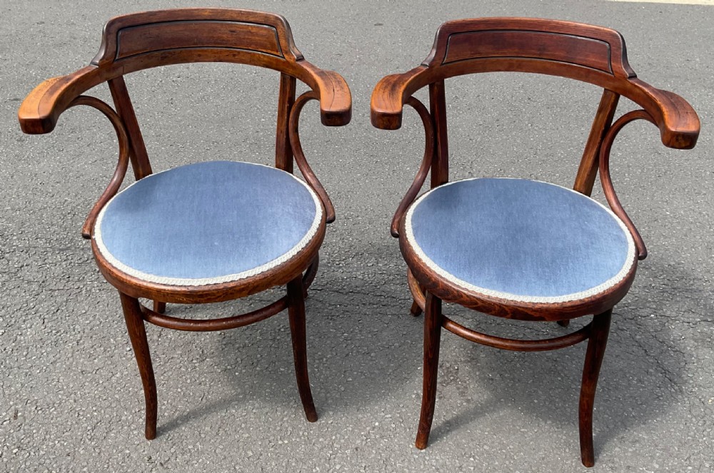 A pair of dark brown bentwood armchairs featuring curved cresting rails, sweeping armrests, and circular blue velvet padded seats.