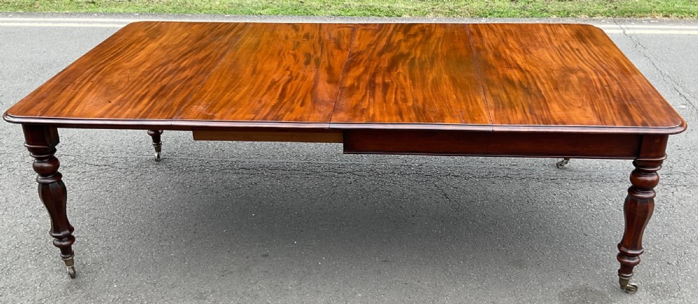 A large William IV mahogany extending dining table with additional leaf inserts, turned legs, and brass castors.