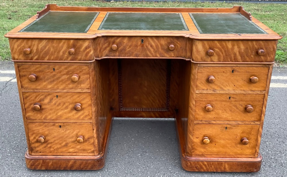 Victorian satin birch pedestal desk featuring a three-part green leather top inset and nine drawers with turned wooden handles.