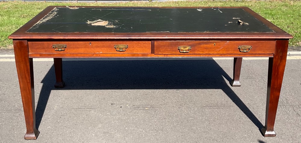 An Edwardian mahogany partners writing desk featuring an inset green leather top, frieze drawers with brass handles, and tapered legs.