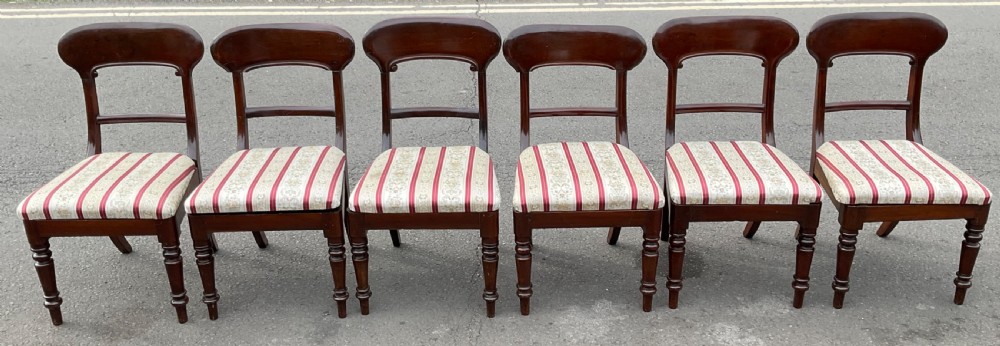 A set of six Victorian mahogany balloon-back dining chairs featuring turned front legs and red and cream striped fabric seats.