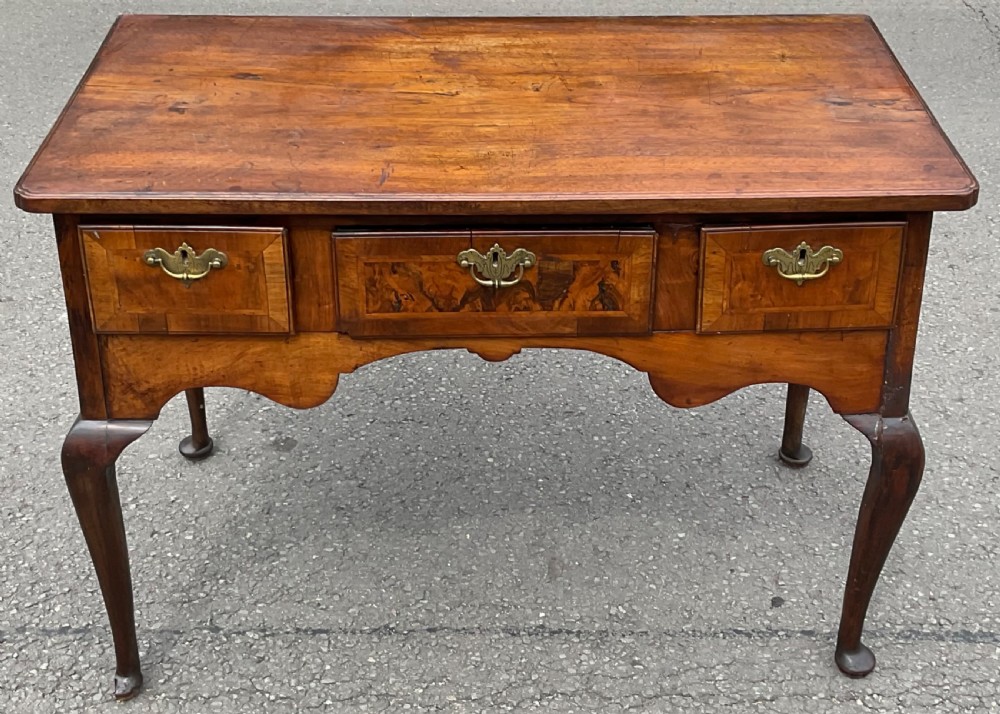 An 18th-century Georgian walnut side table featuring three drawers with brass handles, a shaped lower apron, and cabriole legs ending in pad feet.