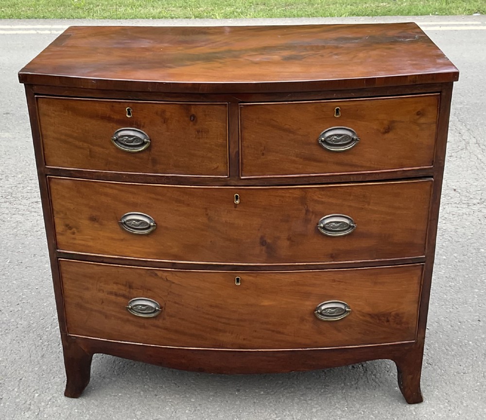 A Georgian mahogany bowfront chest of drawers featuring two short drawers over two long drawers with brass oval handles and curved bracket feet.