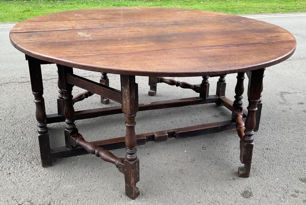 A large circular antique oak double gateleg dining table with turned baluster legs and drop-leaf extensions.