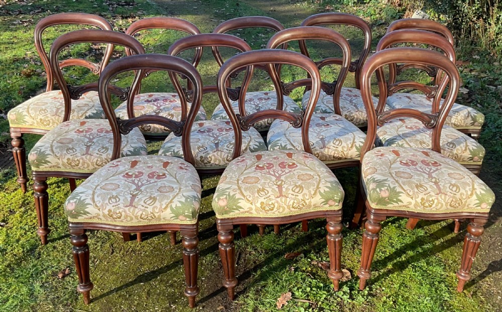 A set of twelve Victorian mahogany balloon back dining chairs featuring turned front legs and patterned upholstered seats.