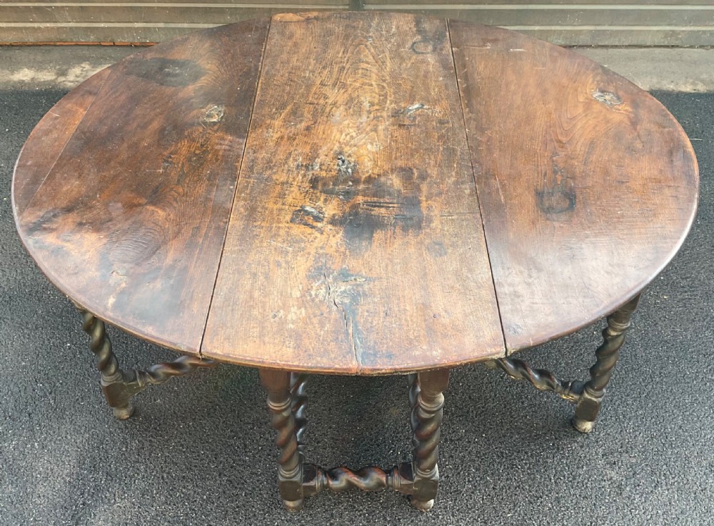 A large antique dark oak gateleg dining table shown extended with round drop leaves and barley twist turned legs. View IV