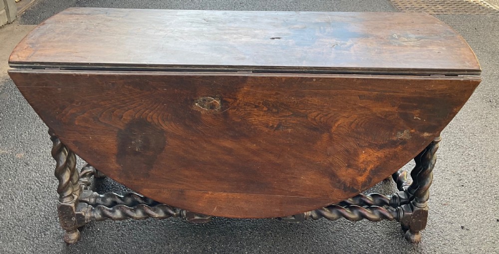 A large antique dark oak gateleg dining table shown extended with round drop leaves and barley twist turned legs. View VII