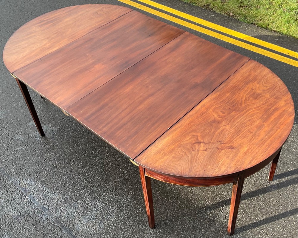 A Georgian mahogany extending dining table featuring two removable leaves, D-shaped end sections, and tapered square legs.