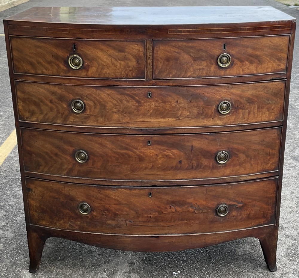 A Georgian flame mahogany bowfront chest of drawers featuring two short over three long drawers with brass ring handles and splayed feet.