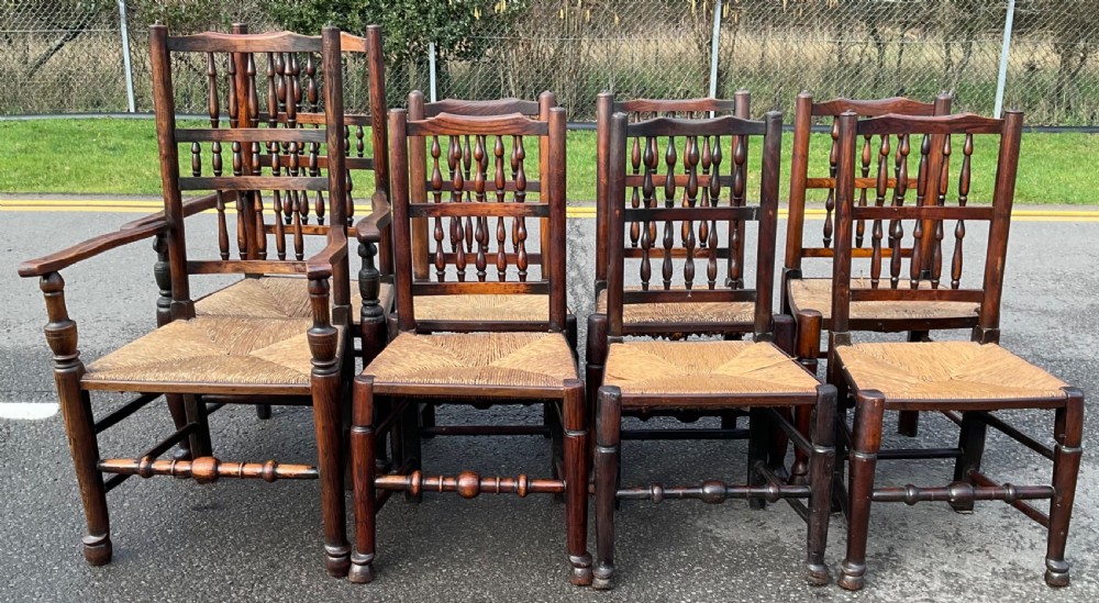 A set of eight Victorian dark elm dining chairs featuring turned spindle backs, side armrests on carvers, and woven rush seats. View IV