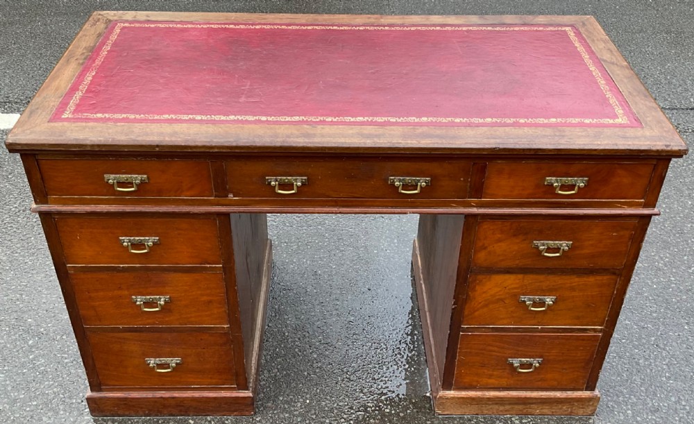 A Victorian mahogany kneehole writing desk featuring a red leather top with gilt tooling and nine brass-handled drawers. View II