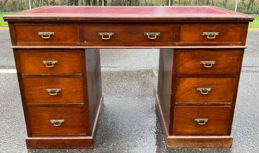 A Victorian mahogany kneehole writing desk featuring a red leather top with gilt tooling and nine brass-handled drawers. View III