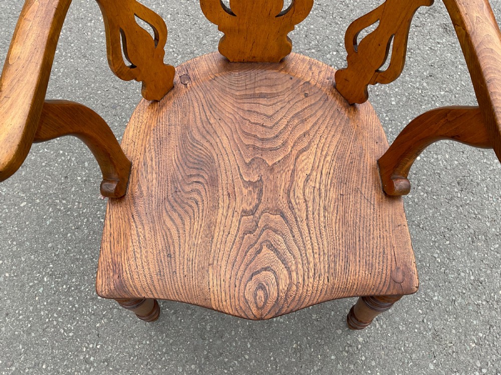 A Victorian elm captains armchair featuring a horseshoe backrest, carved vasiform splats, a shaped saddle seat, and turned legs with stretchers. View III
