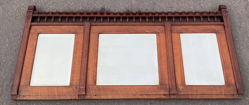 A large Victorian Gothic quarter-sawn oak overmantel mirror featuring three mirror panels and a decorative spindle gallery along the top rail.