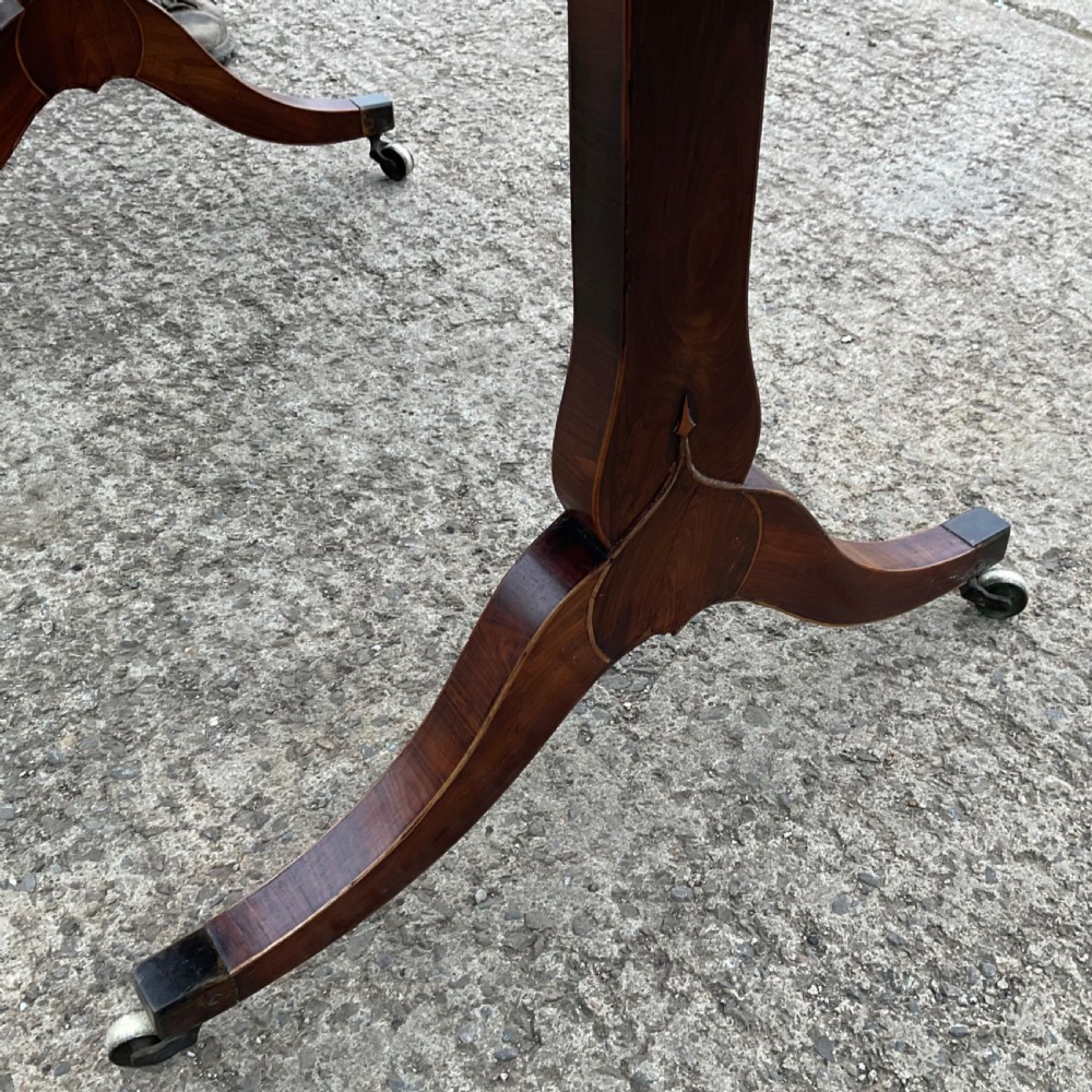 A Regency mahogany sofa table featuring two frieze drawers, drop-leaf ends, decorative string inlay, and splayed legs terminating in brass castors. View IX